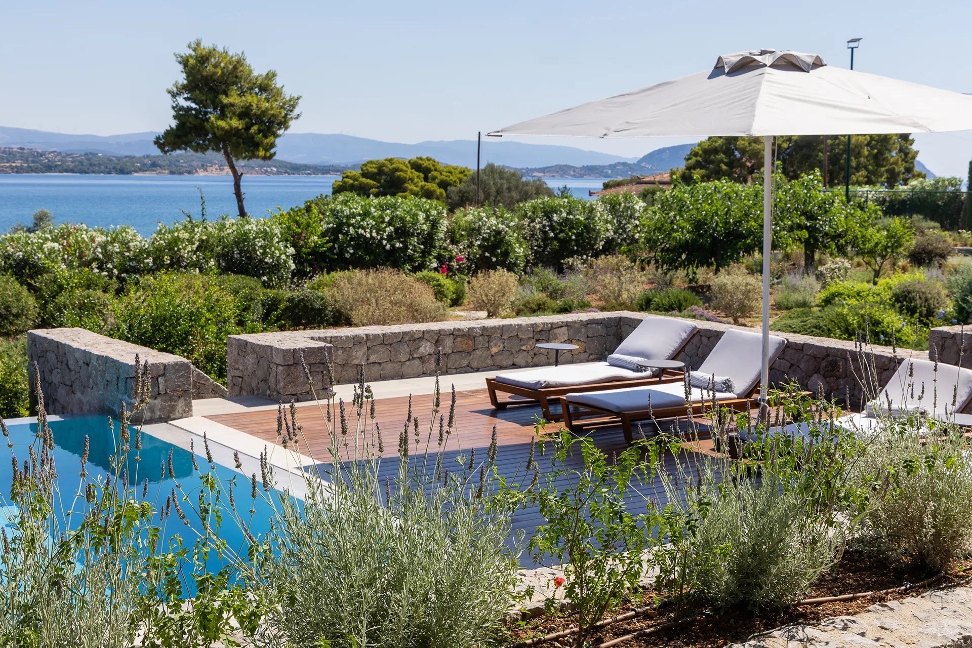 Pool terrace with sun loungers and parasol, Argolic Gulf in the distance
