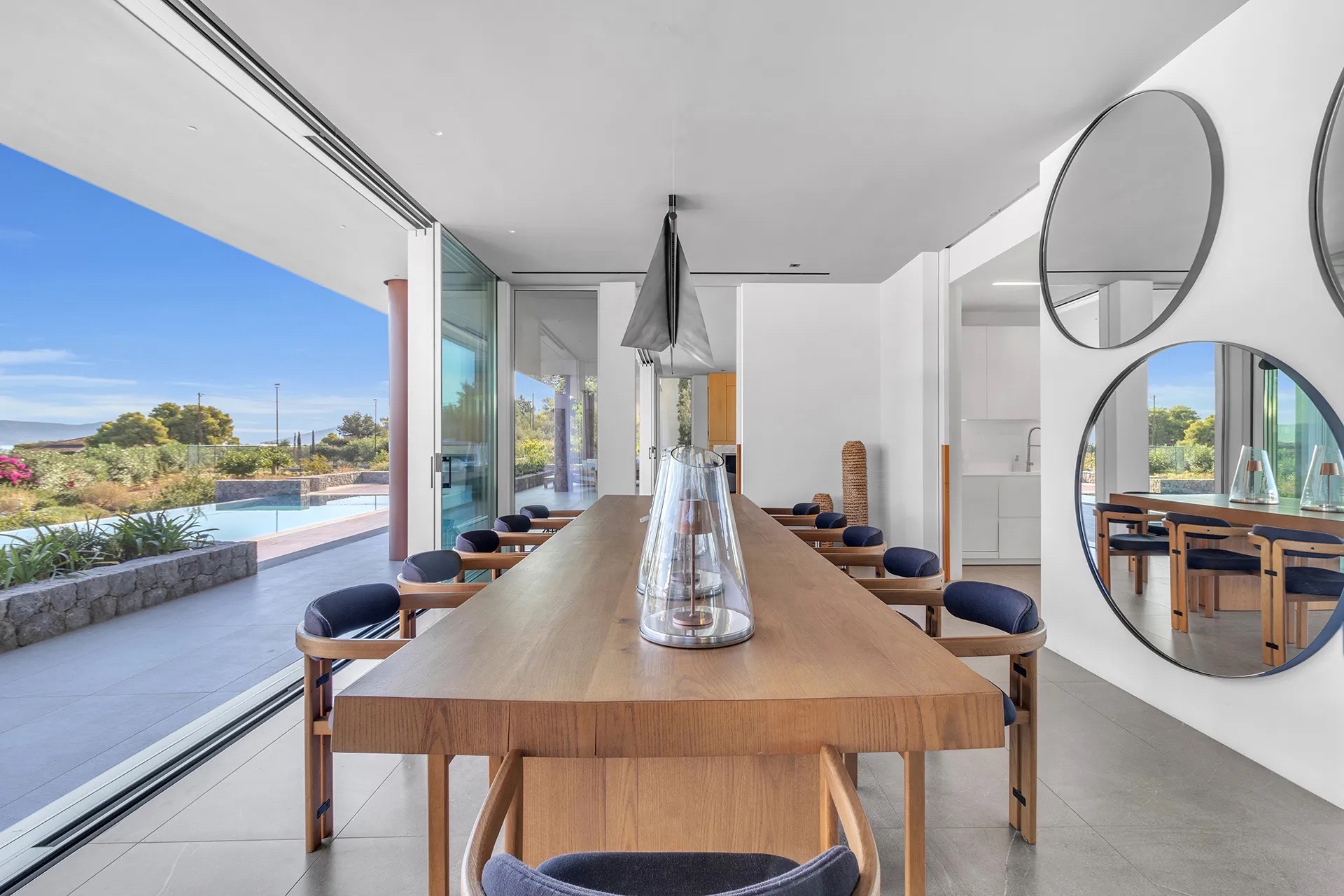 Indoor dining table opening onto the bay, twin circular mirrors on the wall