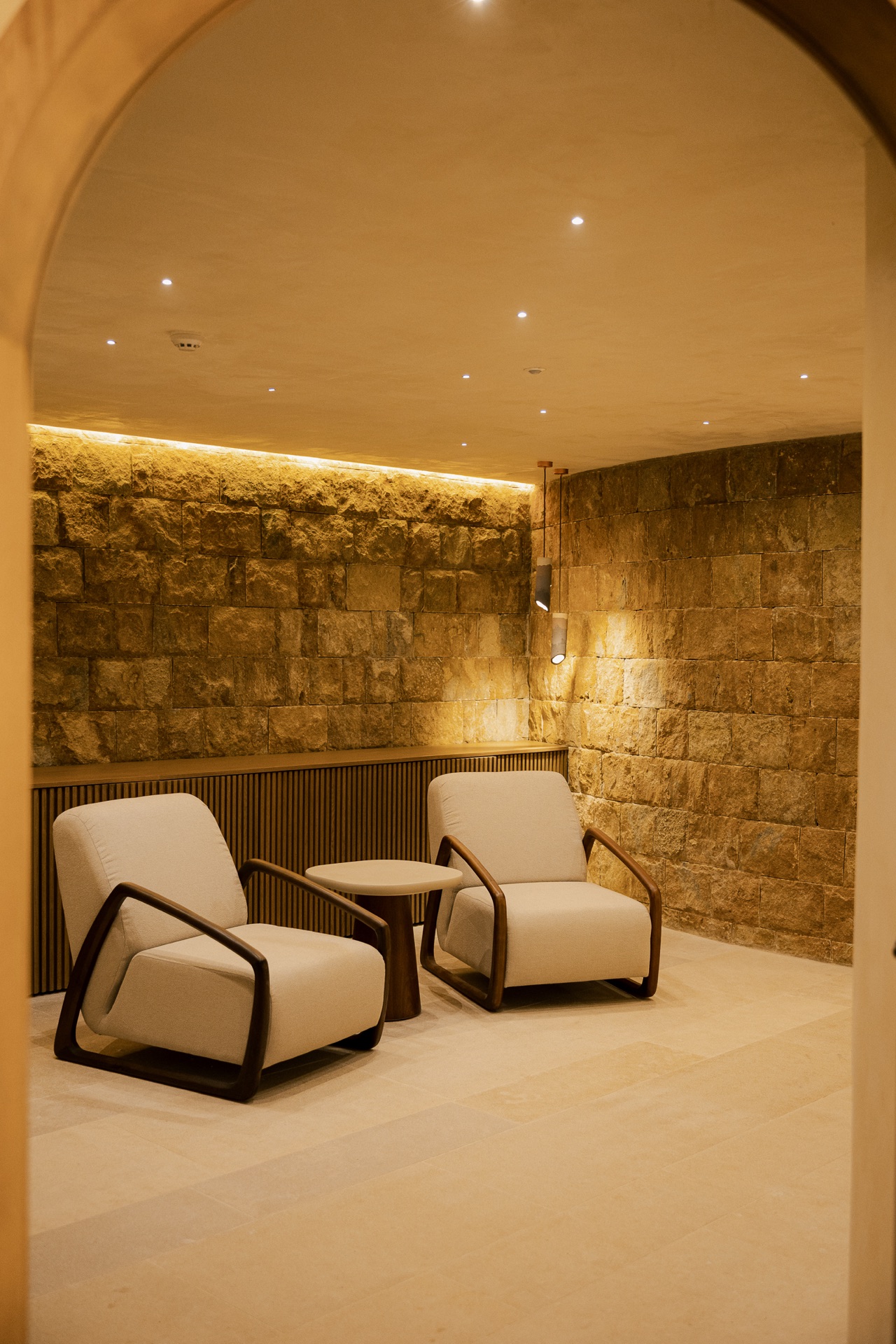 Stone wellness lounge under an arched entry, two armchairs