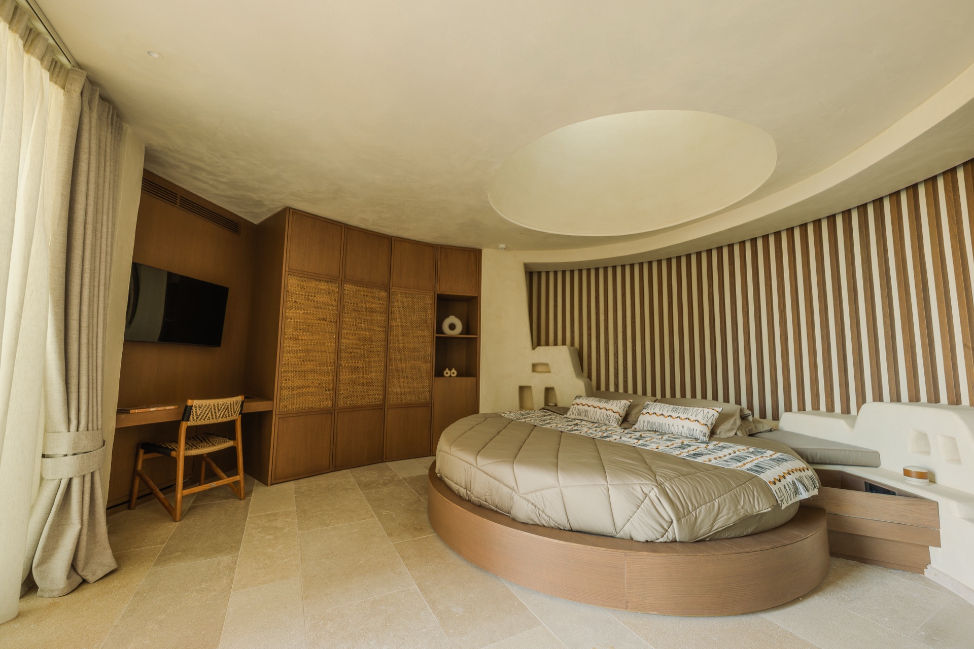 Round bedroom with circular bed, oculus skylight, wooden slat wall