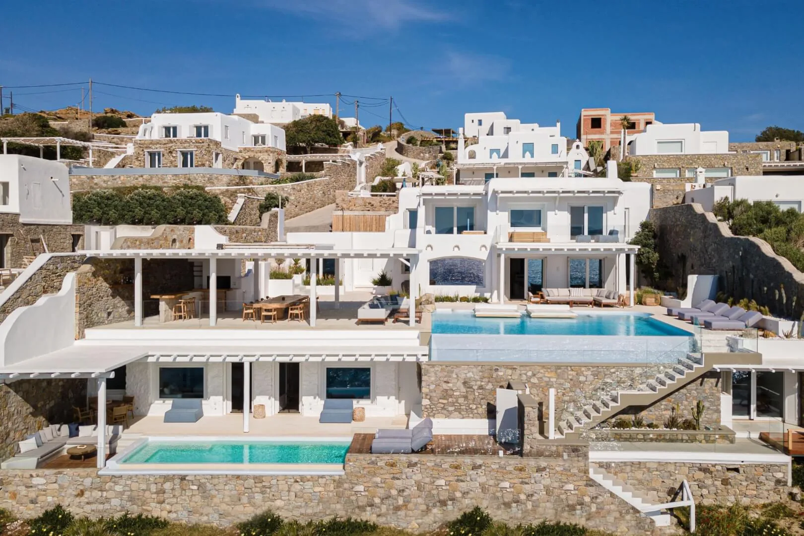 Villa Esmeralda exterior with the infinity pool and lower-wing pool, golden-hour light on stone