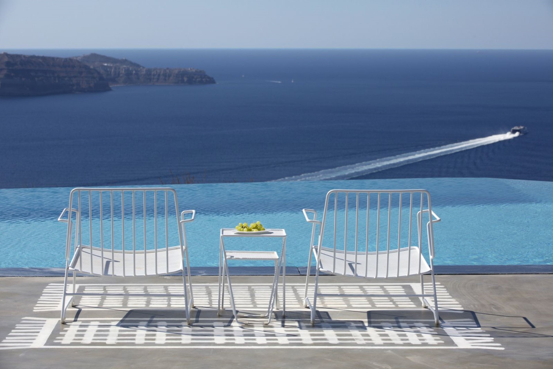 Two chairs at the infinity pool, the Santorini caldera beyond