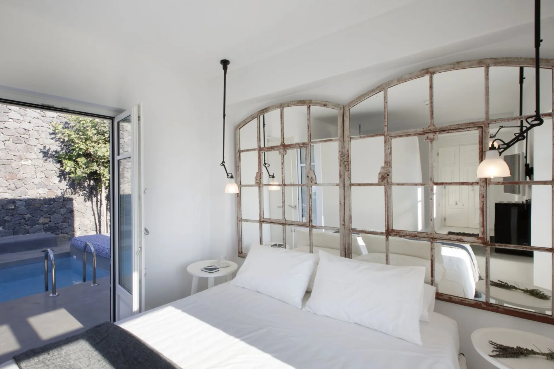 Bedroom with vintage industrial mirrors, plunge pool framed at the door