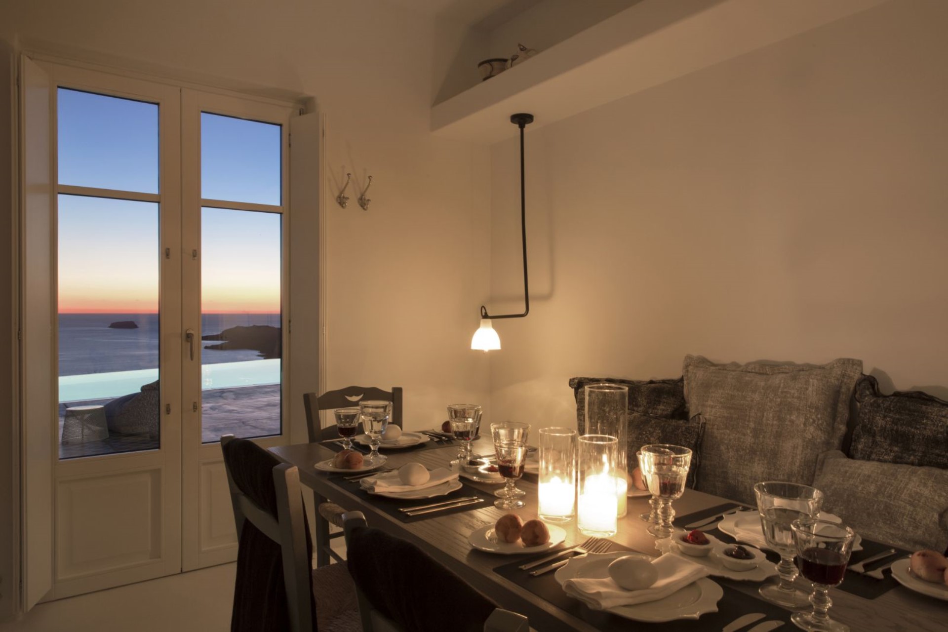 Candlelit dinner table, Santorini sunset through the open doors