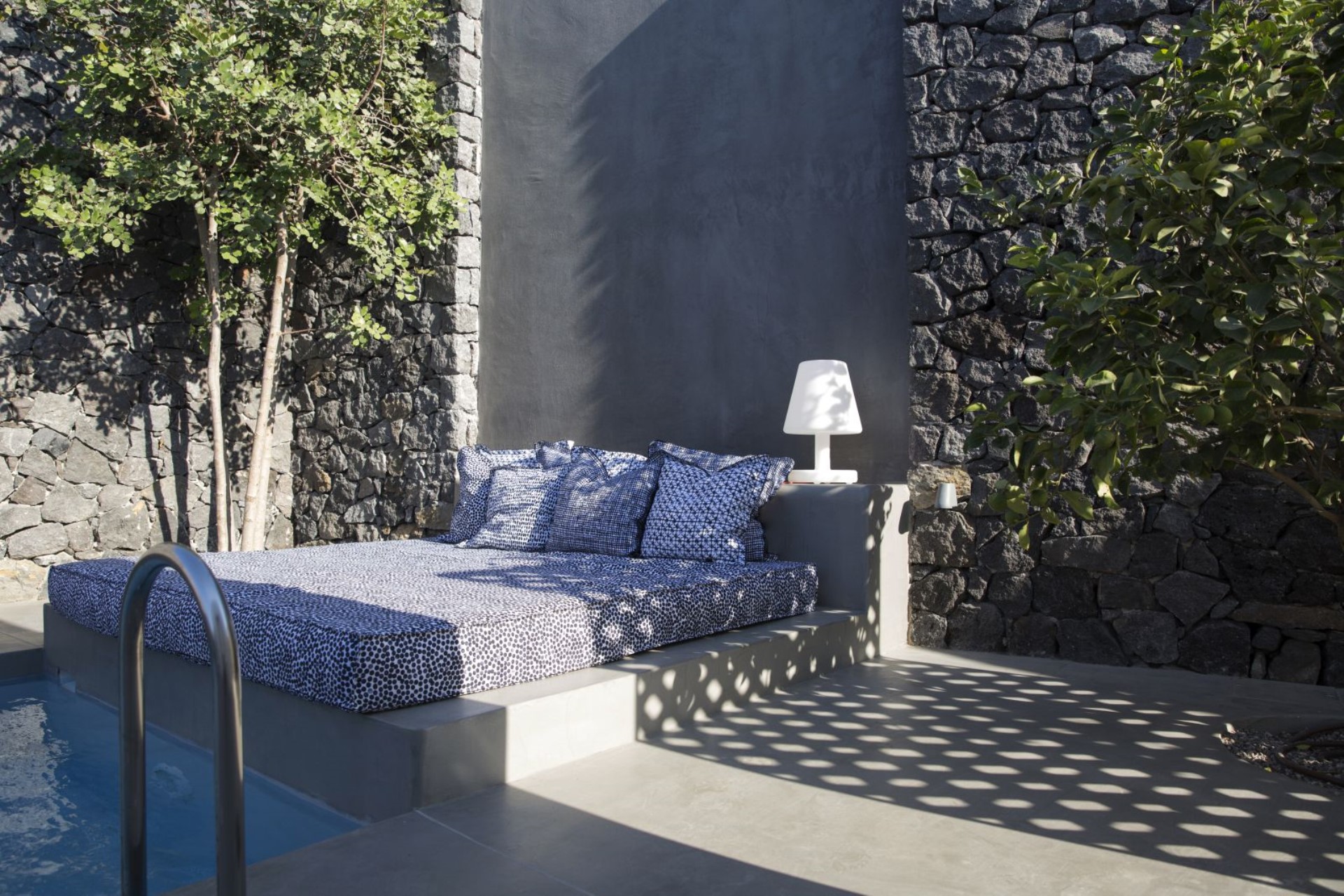 Outdoor lounge in volcanic stone, daybed shaded for siesta