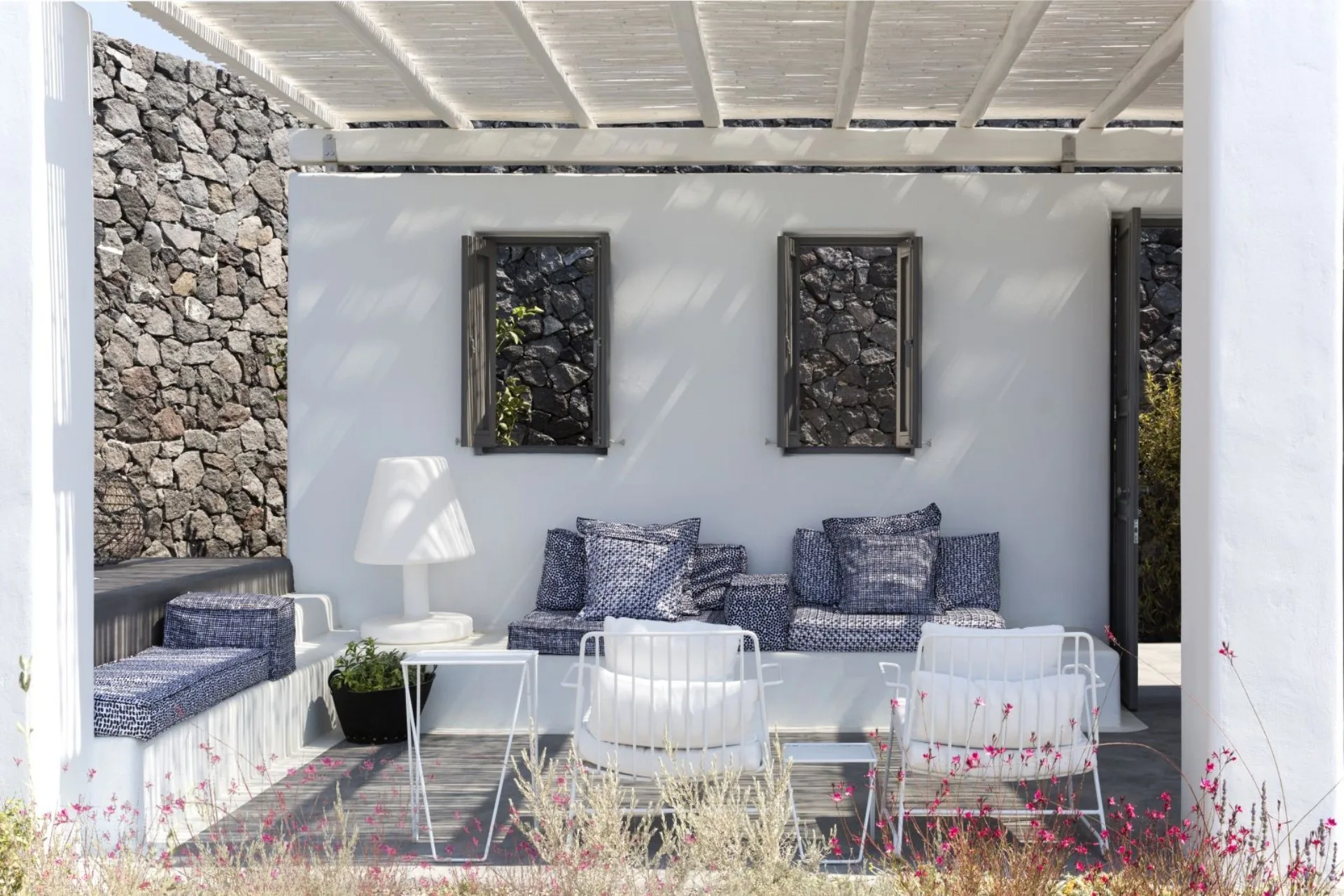 Pergola lounge with blue cushions, wildflowers in the foreground