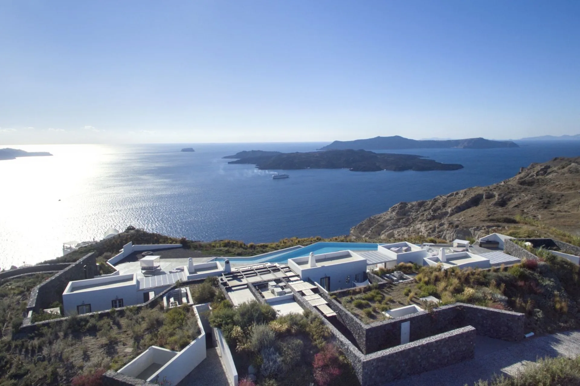 Aerial of the estate above the caldera, the volcano and the open Aegean beyond