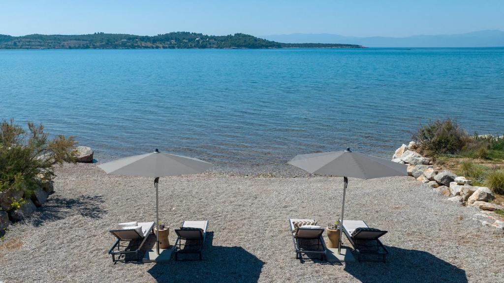 Private beach with two parasols and lounge chairs facing the bay