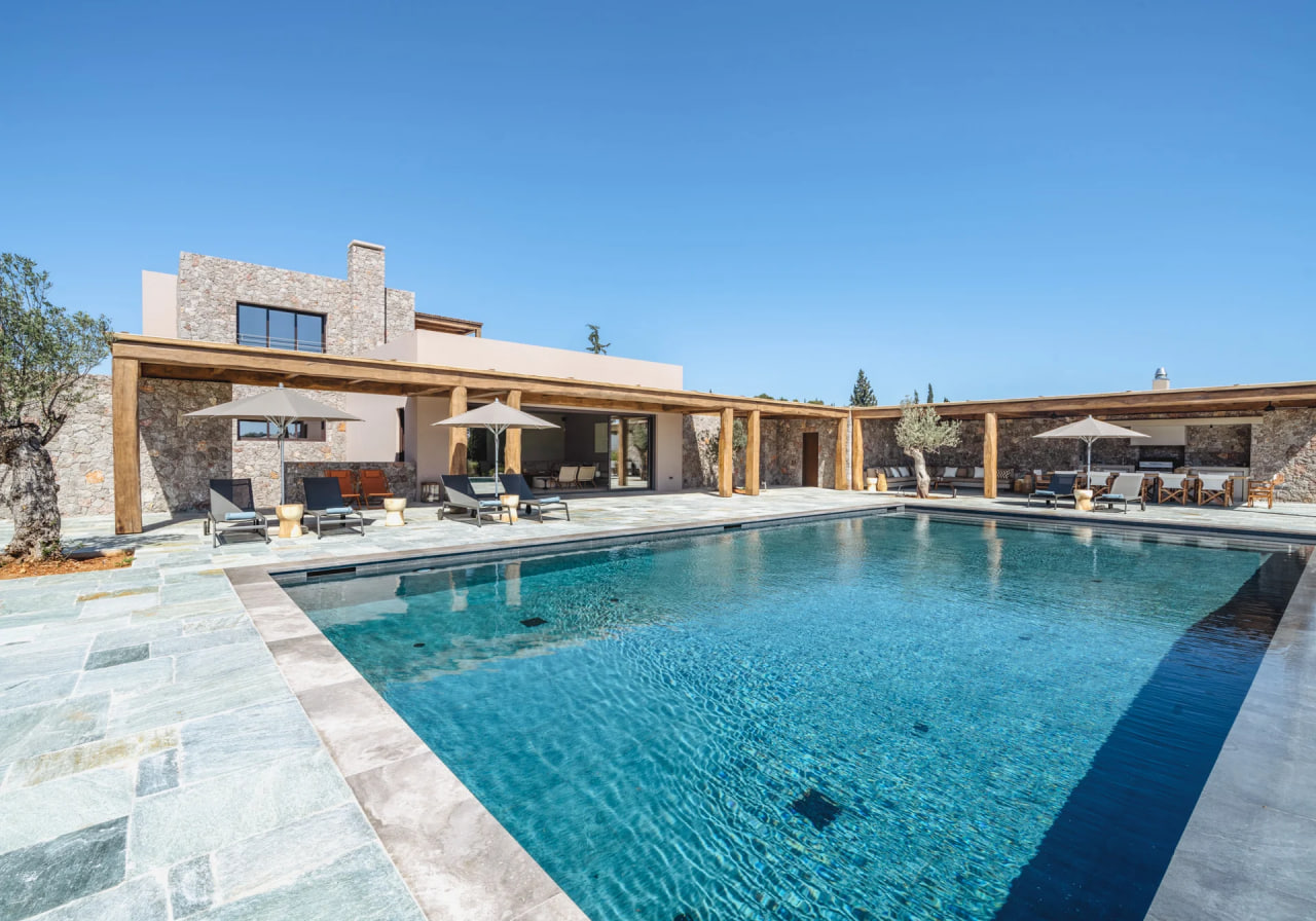 Long pool flanked by parasols and lounge chairs, the villa beyond