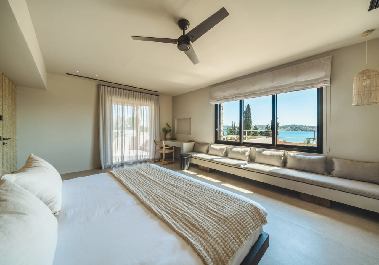 Master bedroom with built-in bench and large windows onto the sea