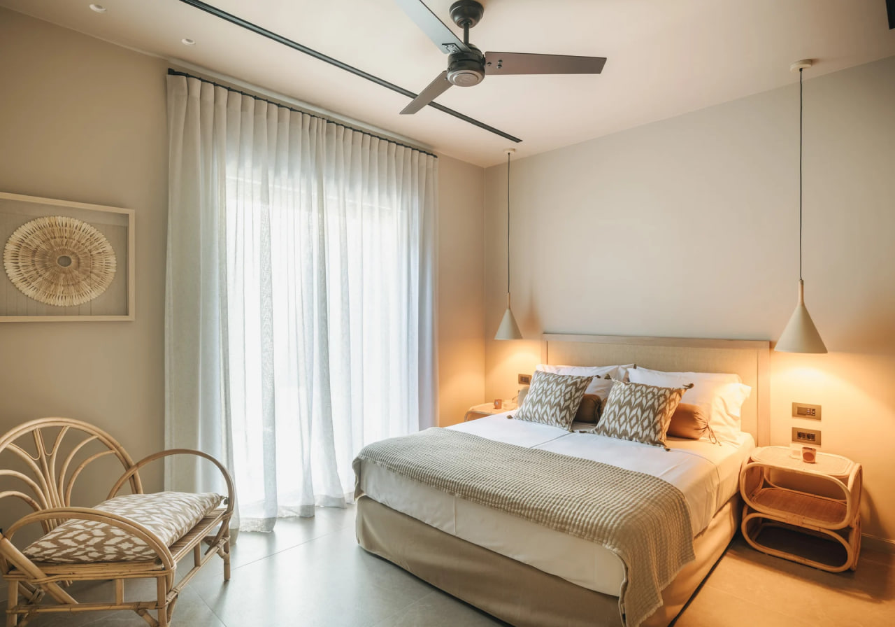 Guest bedroom in soft beige tones, sheer curtains, rattan chair