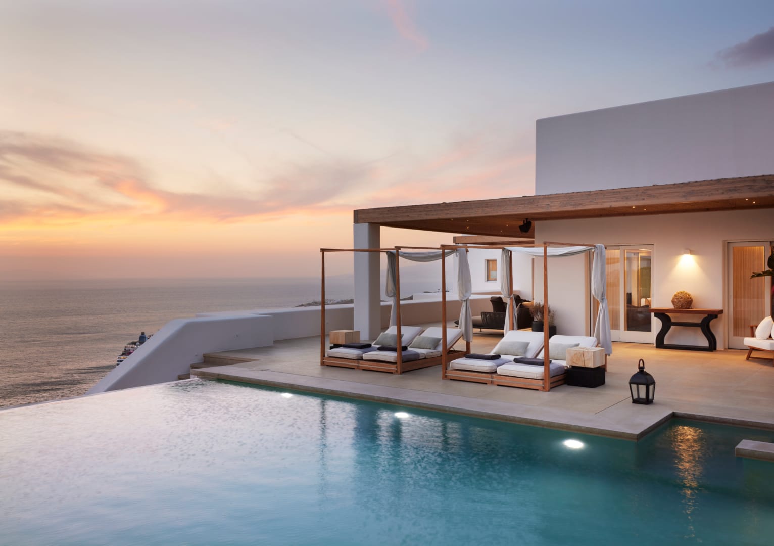 Pink and gold sunset over the canopied daybeds and infinity pool