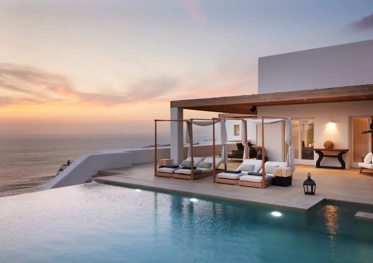 Pink and gold sunset over the canopied daybeds and infinity pool