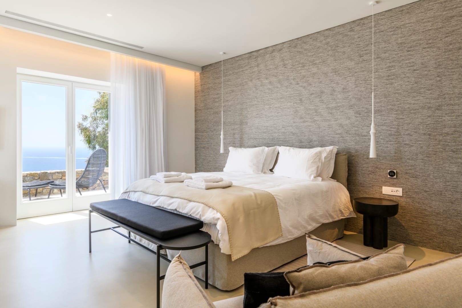 Bedroom with grey textile headboard and morning sea view