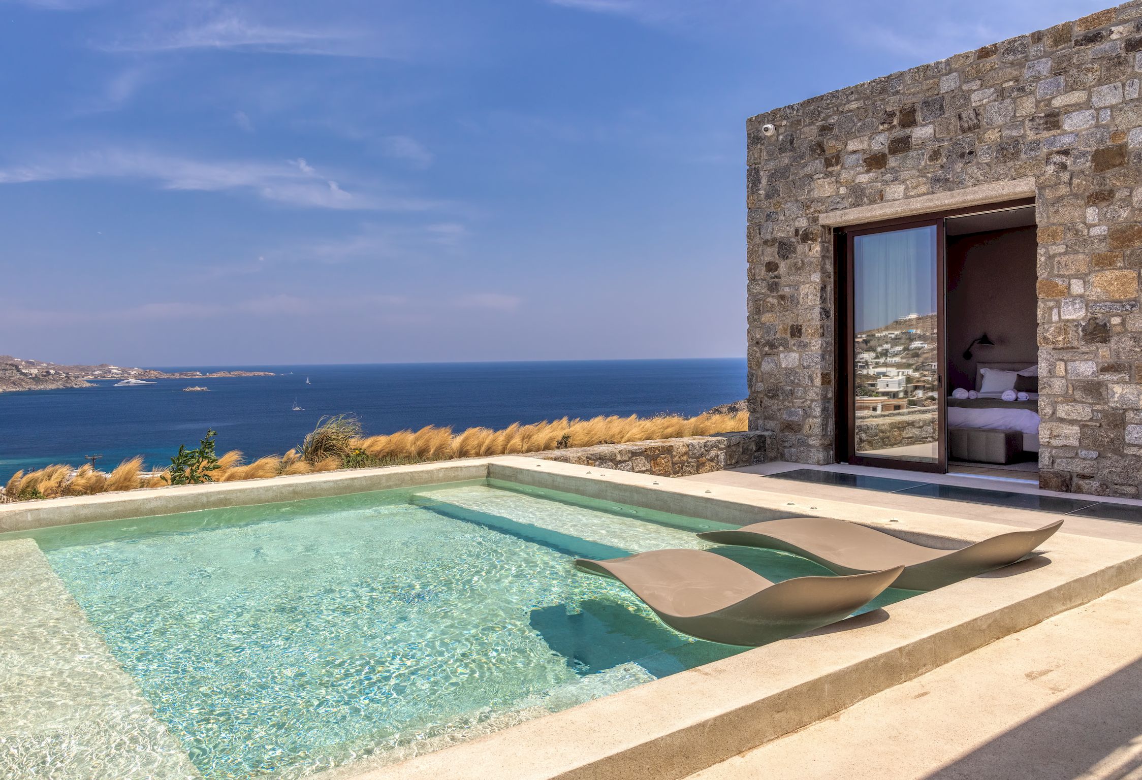 Plunge pool set in stone, Aegean opening beyond the terrace